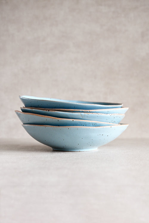A stack of four light blue ceramic bowls with a speckled glaze and a thin brown rim.  Bowl Plates on sale In Singapore