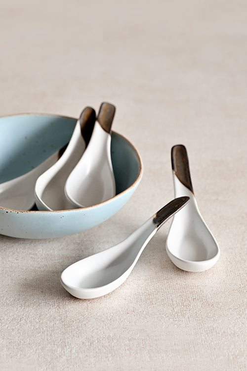 Gold leaf ceramic soup spoon resting inside a matching ceramic bowl