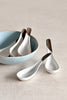 Gold leaf ceramic soup spoon resting inside a matching ceramic bowl