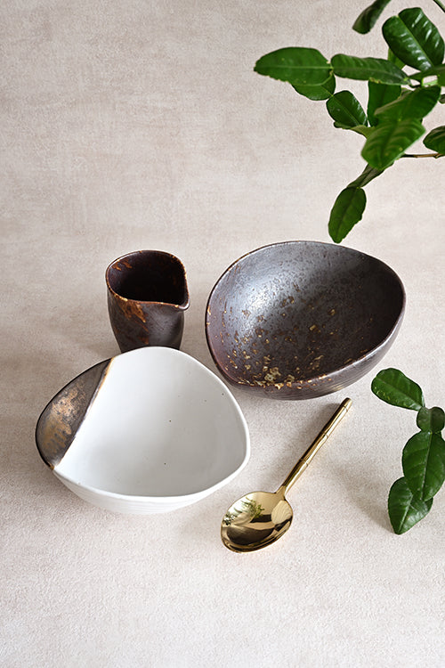 The Intimate Table set — Charcoal Grill Shell Sharing Dish, Pouring Jar, Gold Leaf Shell Bowl, and Bamboo Polished Gold Serving Spoon, top-down view