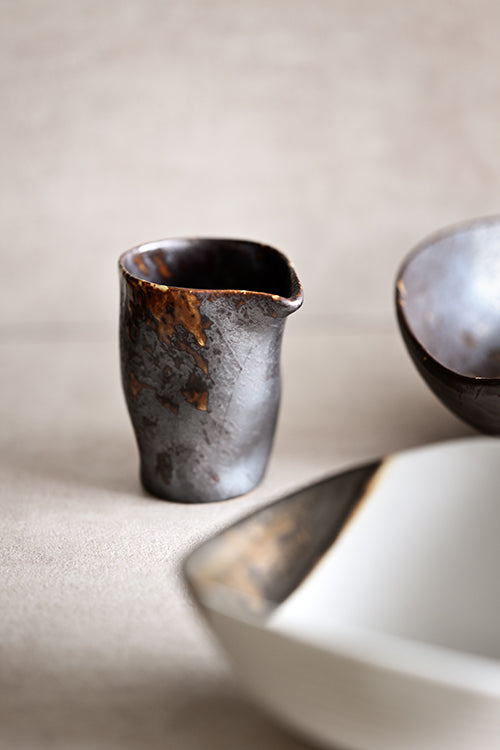 Close-up of the Charcoal Grill Pouring Jar — textured charcoal-and-caramel ceramic with a clean-pour spout for sauces and dressings