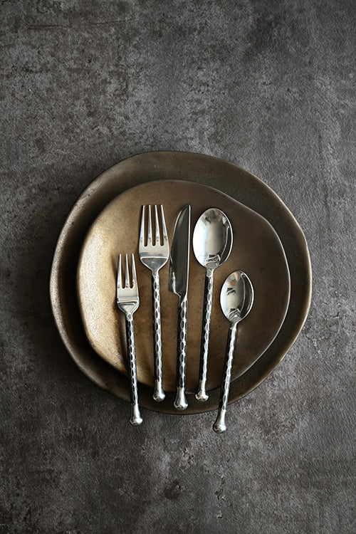 Set of silverware on a dark plate against a gray background